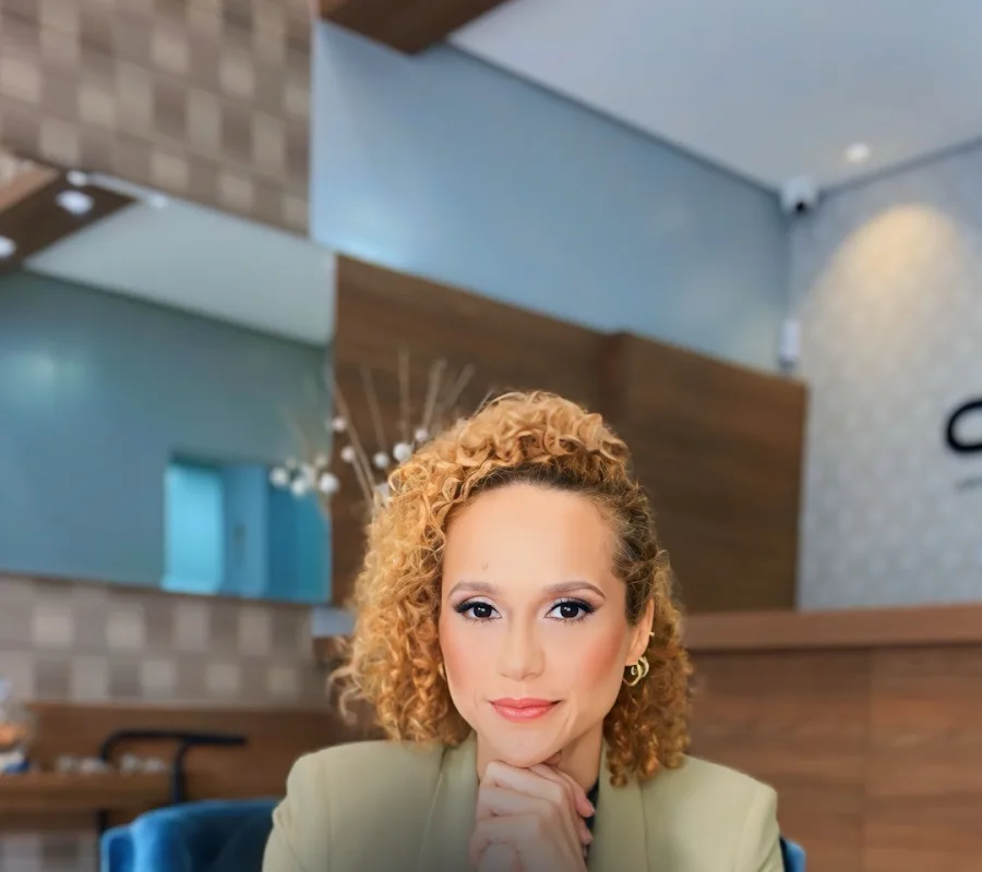Dra. Graciely Borges sentada em poltrona azul na clínica
