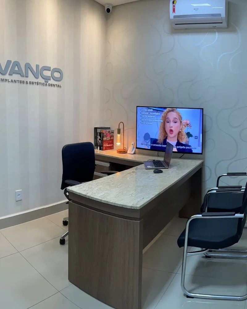 Sala de atendimento com mesa, cadeiras e televisão